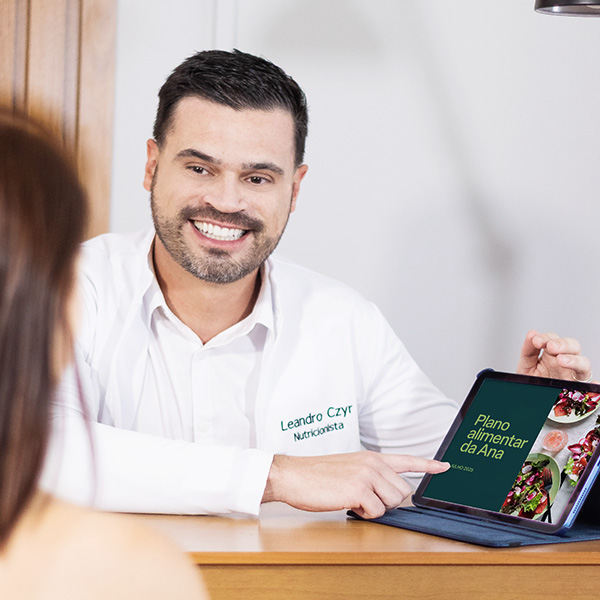 Nutricionista apresentando um plano alimentar digital em um tablet durante consulta clínica.